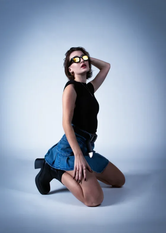Artista de rodillas con pollera de jean y botas