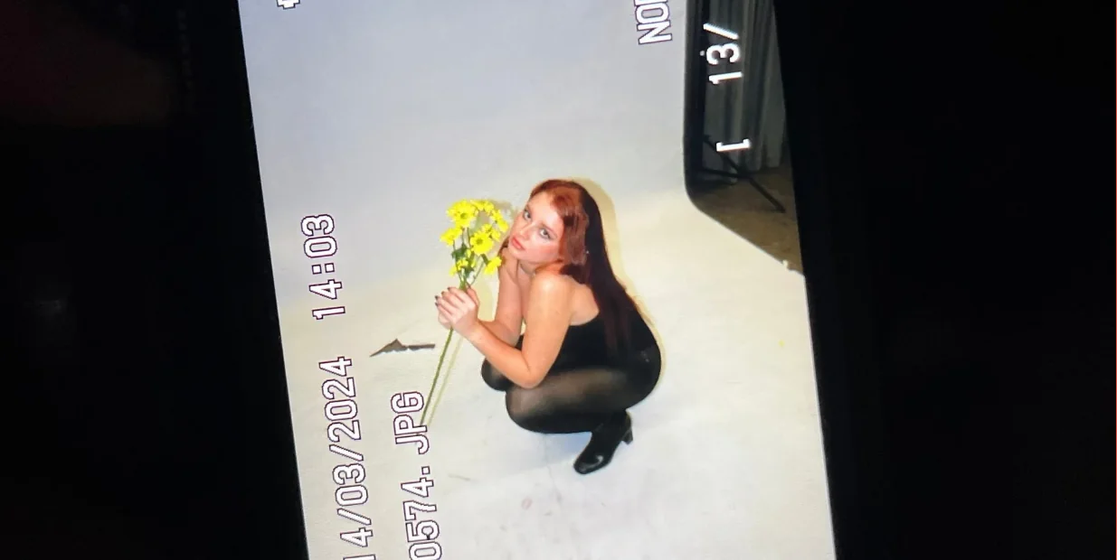 Pantalla de la cámara durante una sesión: modelo con flores amarillas sobre fondo blanco